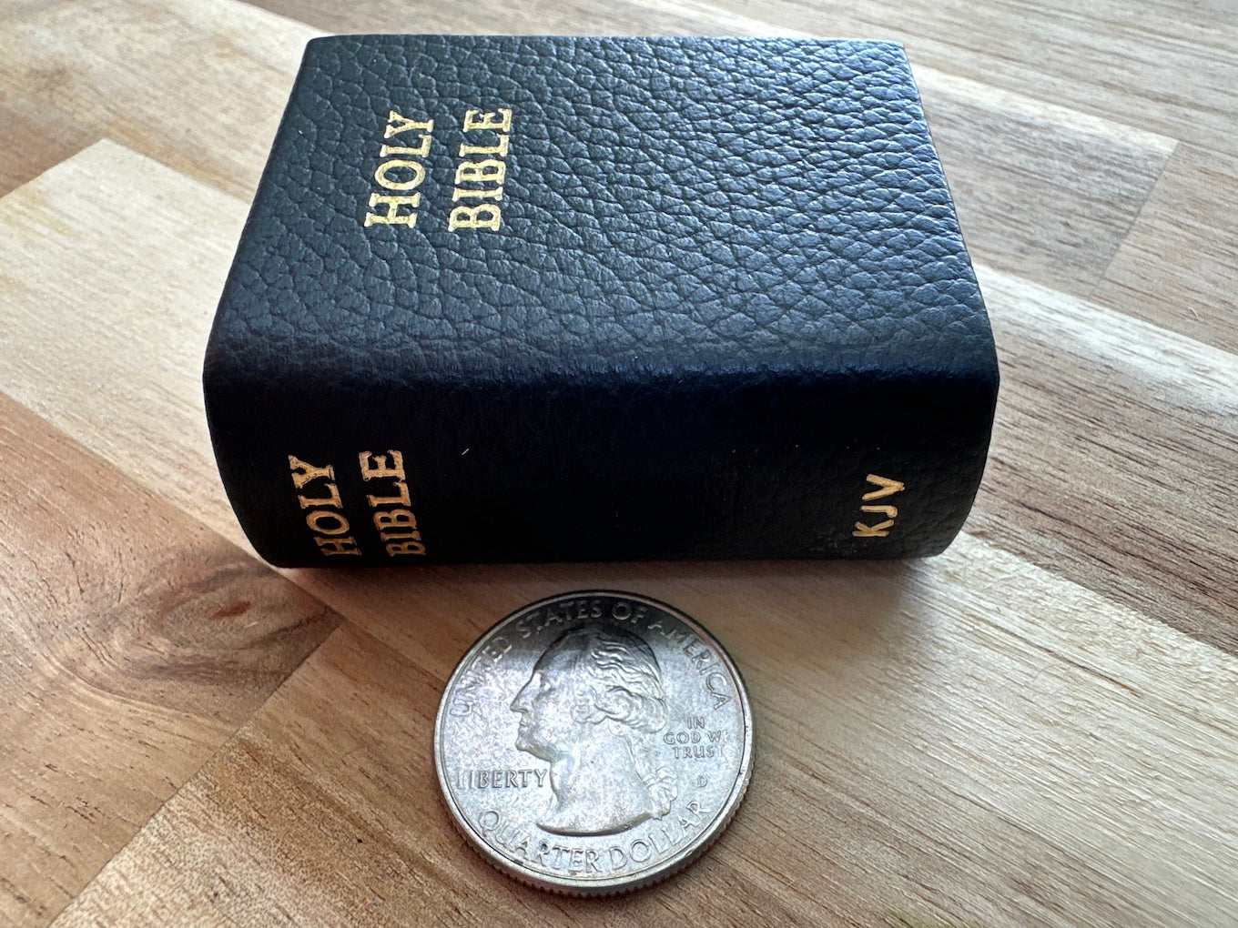 Tiny Bible compared to a quarter coin.